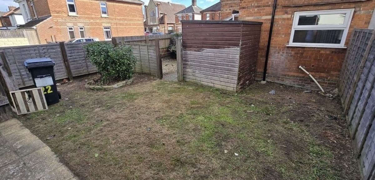 Small rear garden with long grass and weeds cut right back