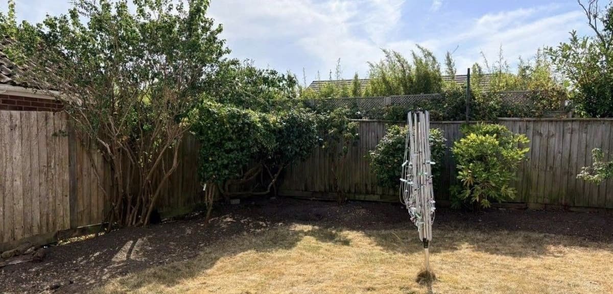 Overgrown shrubs reduced to reveal the fence line and a clean, defined border