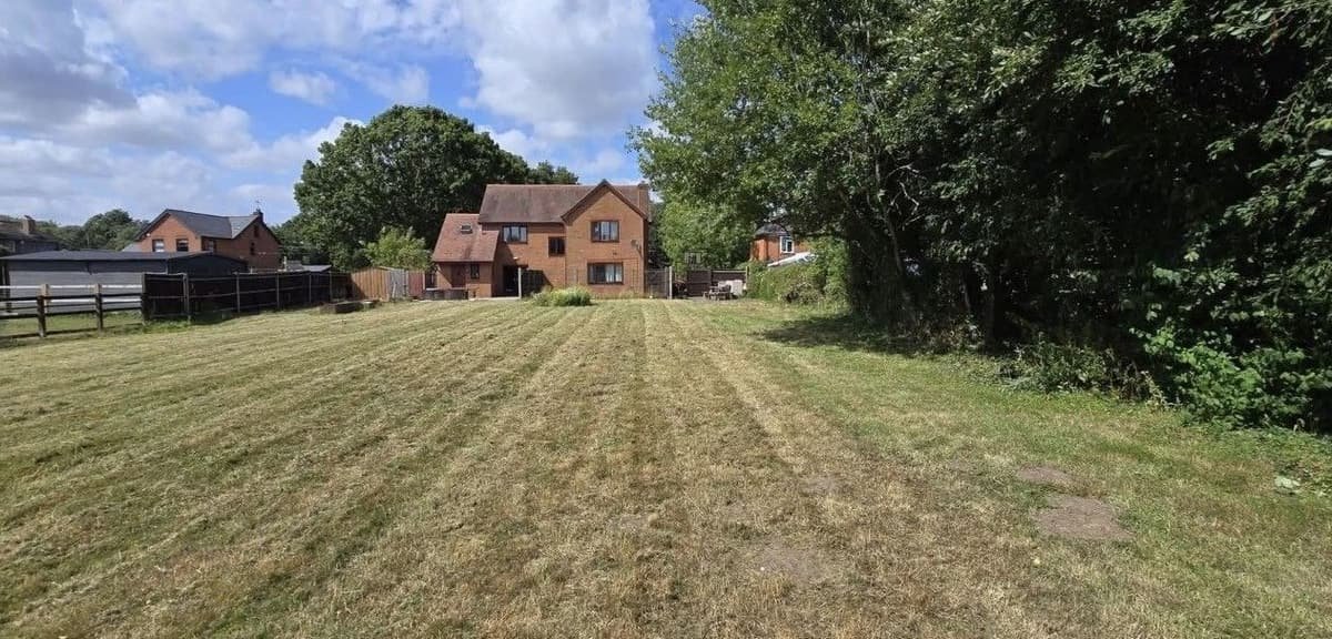 Large open lawn cut with neat stripes leading up to a brick house